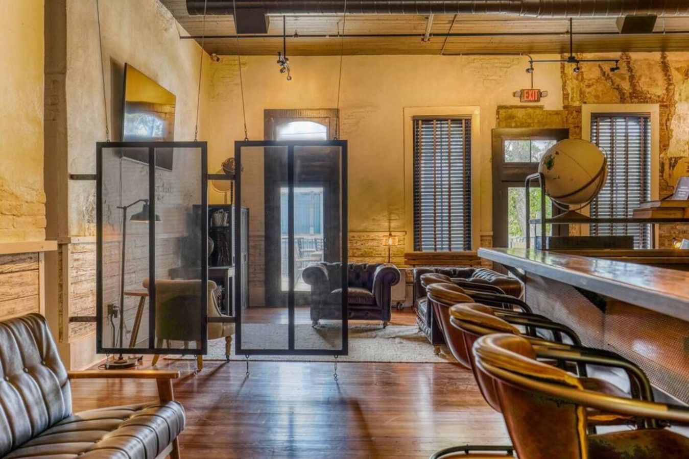 Une salle avec un coin bar, des sièges en cuir et une vue à travers une paroi en verre.