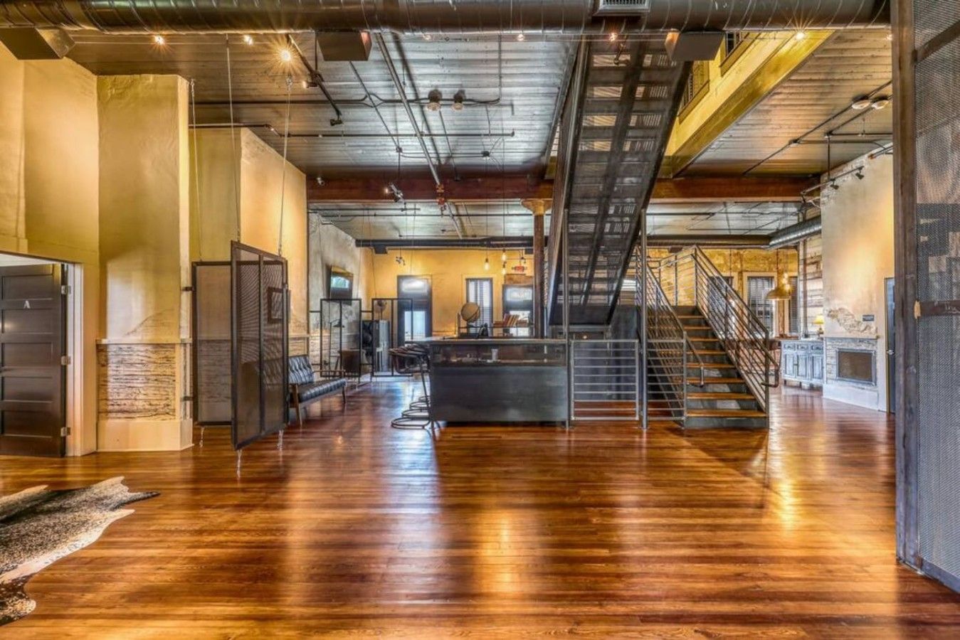 A spacious interior with a central bar area, a staircase, and a mezzanine level.