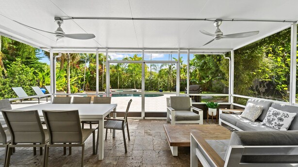 A covered outdoor patio with a pool, seating area, and ceiling fans. - Fort Lauderdale~Saltwater Pool~Near Beach~Spacious (Fort Lauderdale)