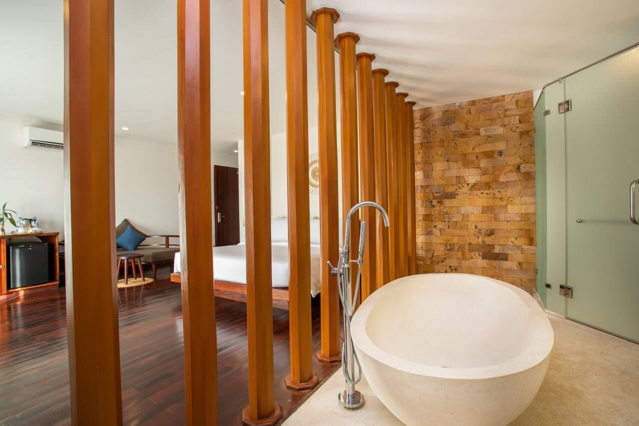 A bathroom with a large bathtub, wooden pillars, and a brick wall.