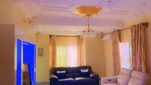 Ein Wohnzimmer mit einem schwarzen Ledersofa, einem weißen Sessel und einer Chandelier.