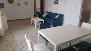 A room with a white table, blue chairs, a teal sofa, and a white desk. - 3354 - LA SOLANA 3-28 VERY GOOD SITUATION, 2ND LINE OF THE BEACH (80m) IN THE URBANIZATION OF SANTA MARGARITA. (Roses)