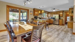 Una cocina amplia con armarios de madera, una isla central y un comedor con una mesa grande y sillas.