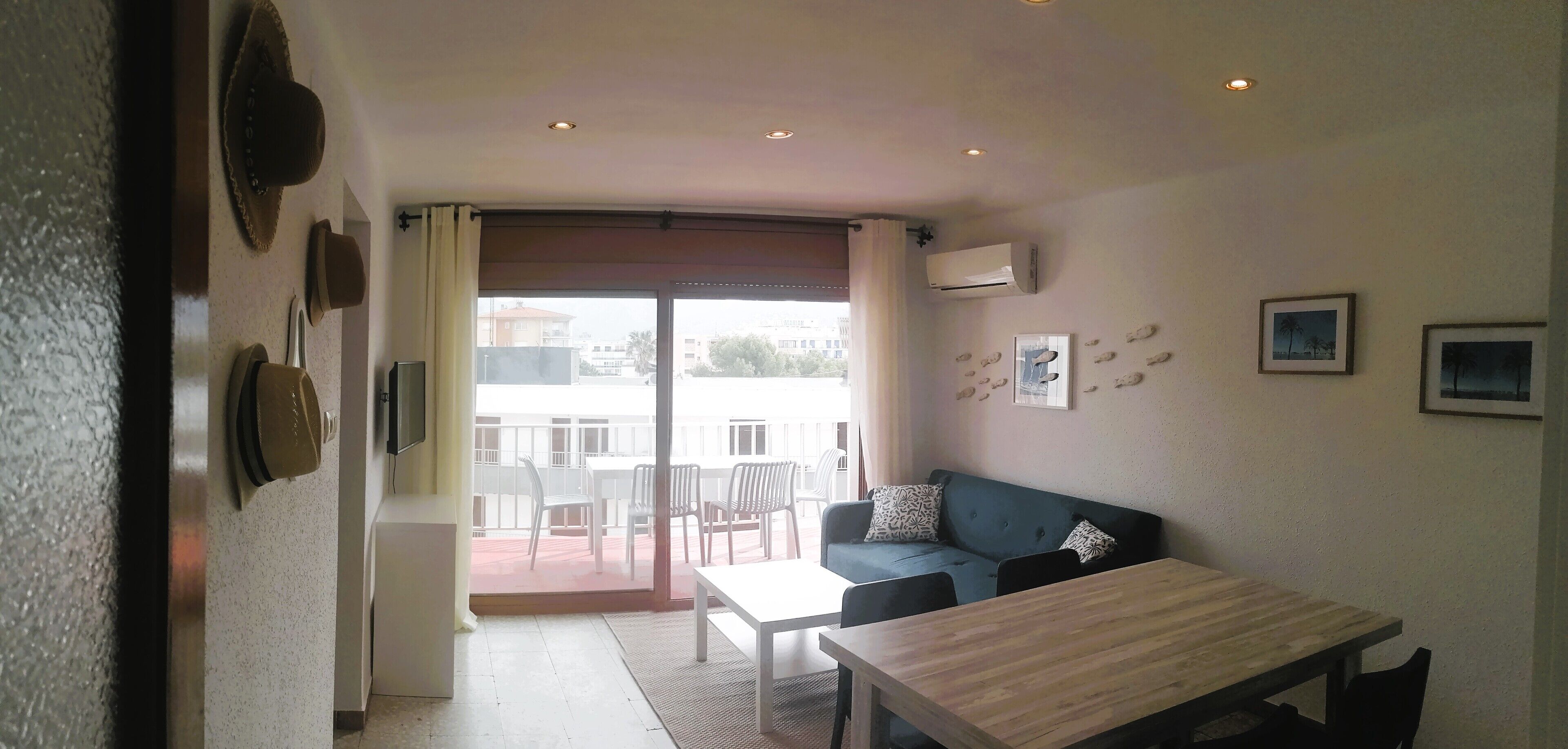 Una habitación con un sofá, una mesa de comedor y vistas a través de un ventanal grande.