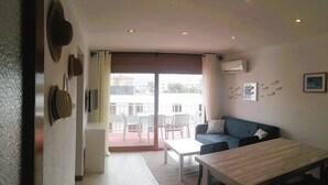 Ein Zimmer mit einer Couch, einem Esstisch und Blick durch ein großes Fenster.