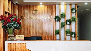 A reception desk with a wooden backdrop, a sign reading "Rose Khung Hotel," and a reception area with a sign that reads "Lê Tân." - Rose Nhung Hotel Catba (Hai Phong)