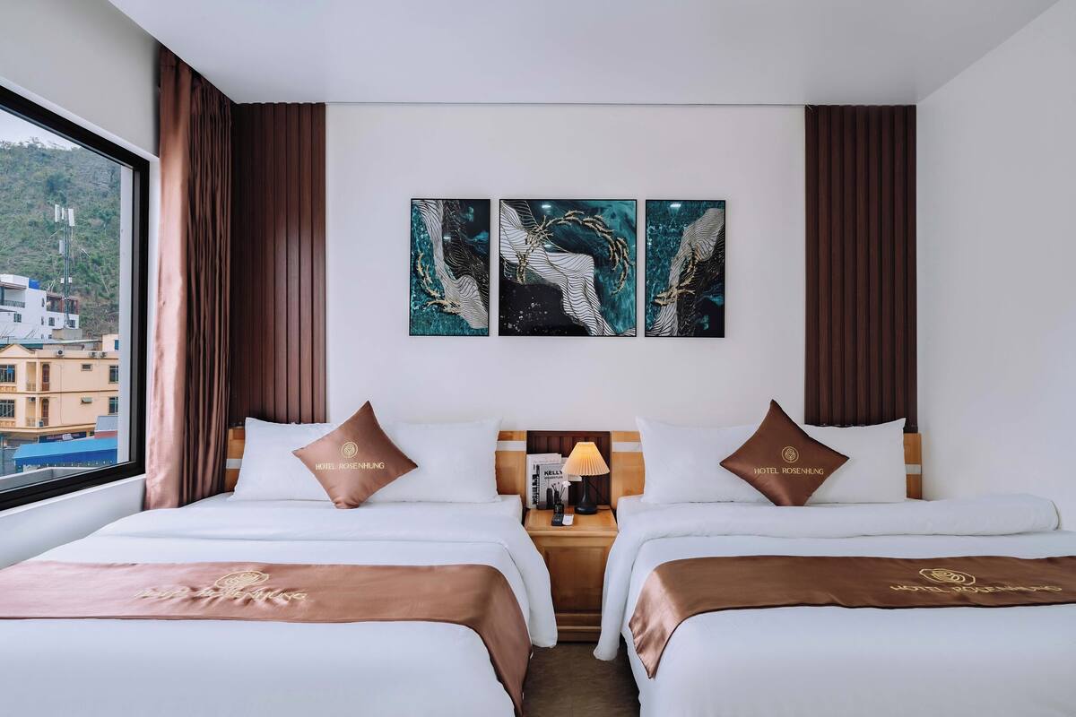 Une chambre d’hôtel avec deux lits, une table de chevet avec une lampe et trois œuvres d’art murales.