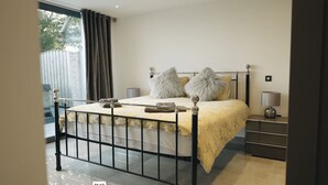 A modern bedroom with a bed, a nightstand, and a window with curtains. - Hollywood vibes in pembrokeshire (Haverfordwest)