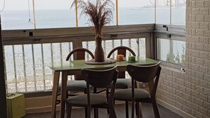 A dining area with a table and chairs, a potted plant, and a view of the sea through large windows. - Apartment in Jounieh, sea view, 6th floor, wifi (Keserouan)