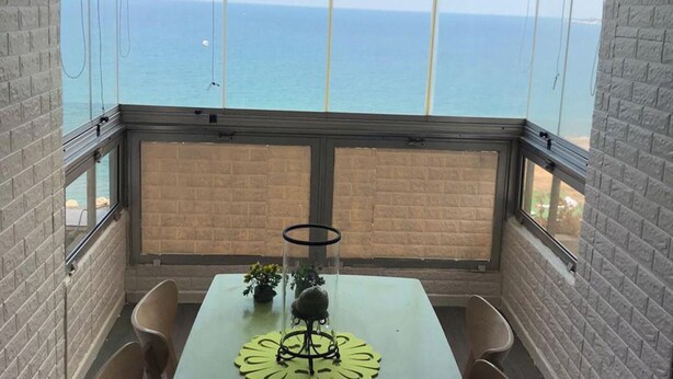 A room with a table and chairs, a view of the ocean, and a brick wall. - Apartment in Jounieh, sea view, 6th floor, wifi (Keserouan)