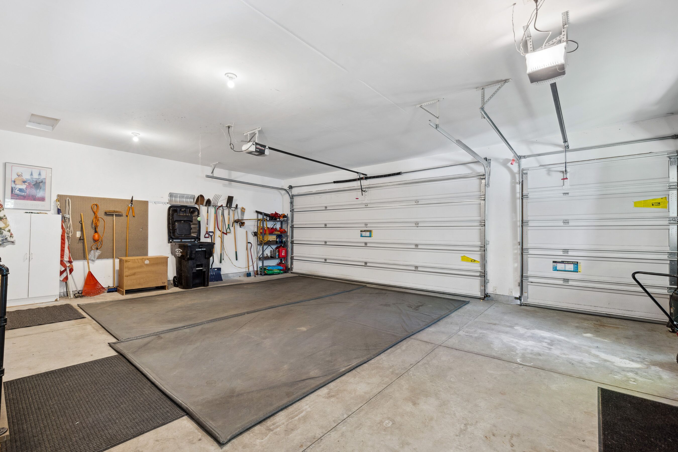Un grand garage comprenant un grand établi, un espace de rangement pour les outils et un projecteur fixé au plafond.