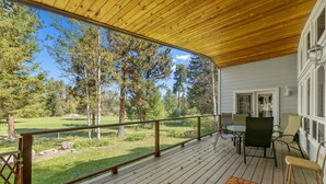 En træterrasse med udsigt over en græsplæne og træer.