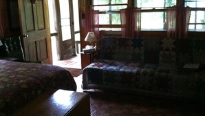 A room with two beds, a sofa, a lamp, and a window with curtains. - Secluded Cabin Nestled In The Trees Overlooking Fishing & Canoe Pond (Burlington Flats)