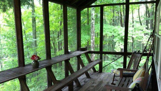 A wooden deck with a bench and a chair, overlooking a forest. - Secluded Cabin Nestled In The Trees Overlooking Fishing & Canoe Pond (Burlington Flats)