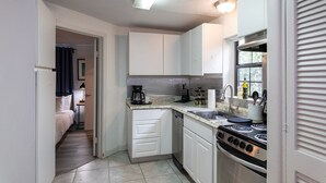 A compact kitchen with white cabinets, a stove, and a sink. - The Queen Sacrifice! Galleria, Medical Center 2BR+1 (Houston)