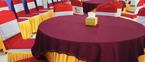 A conference room with round tables, red and white chairs, and a blue ceiling.