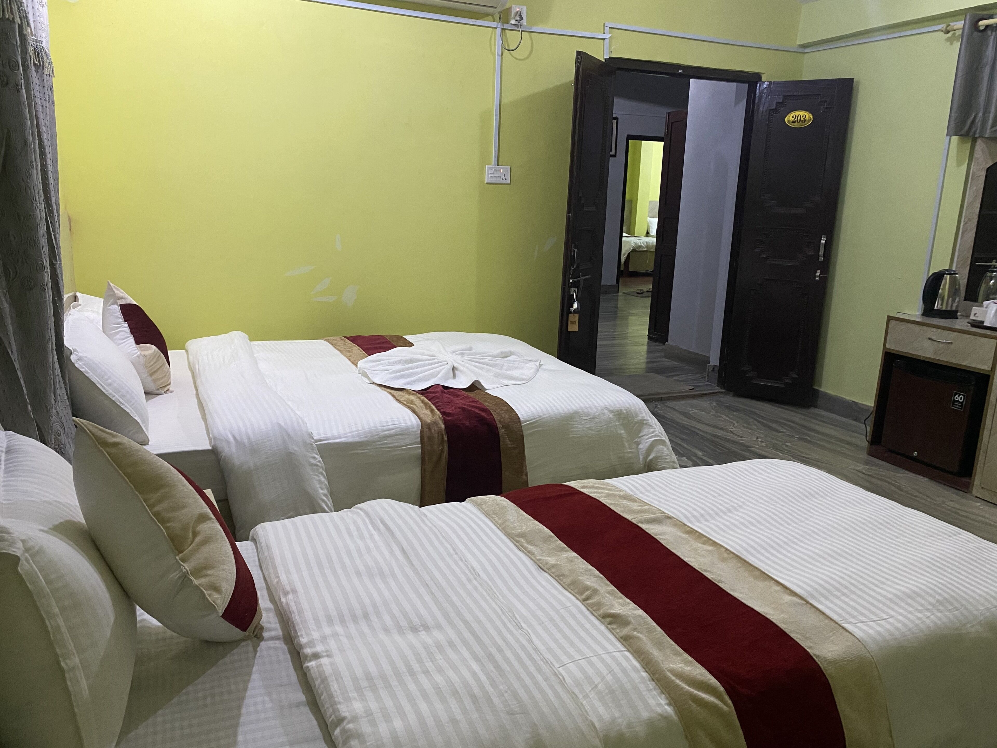 Habitación de hotel con dos camas, un escritorio y un espejo.