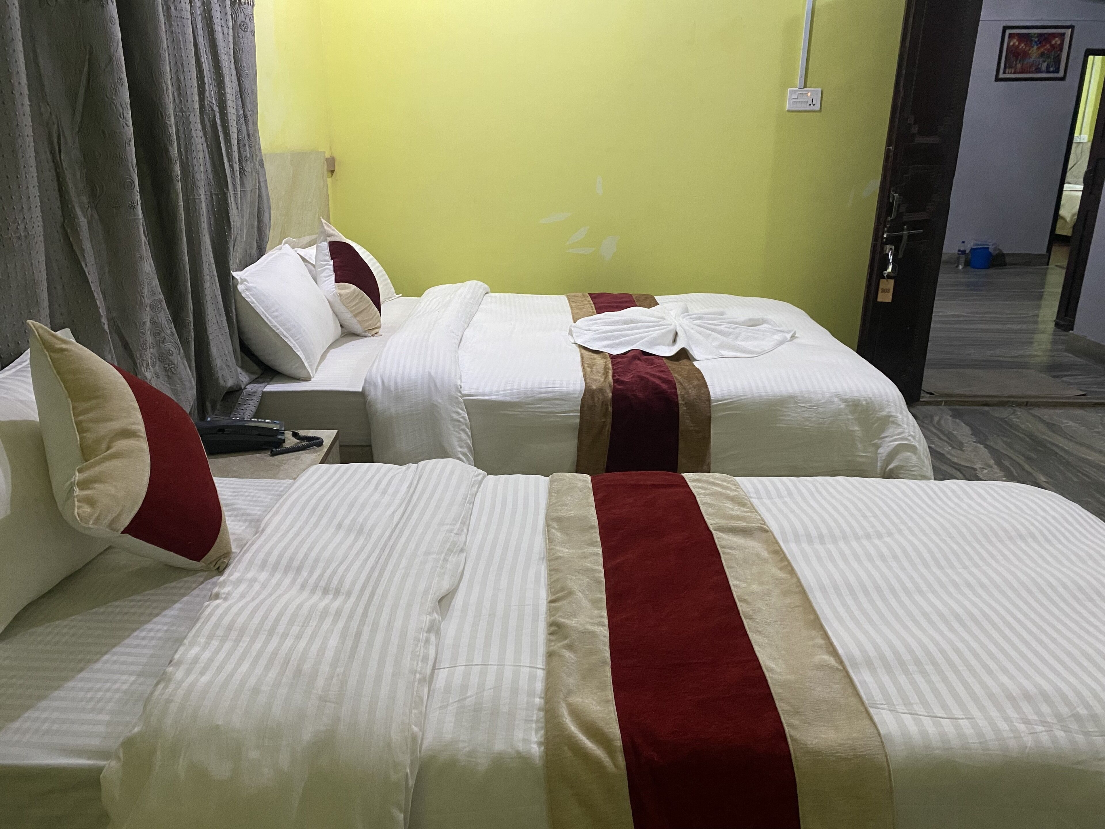 Ein Hotelzimmer mit zwei Betten, jeweils mit weißer Bettwäsche und roten und beigen Akzenten.