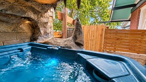 A hot tub with a stone wall backdrop, wooden fence, and a clear sky. - Downtown Chop Shop house, HUGE garage pets allowed (fort smith)