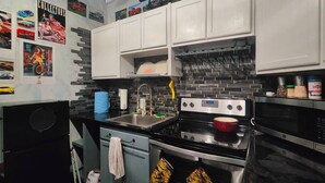 A kitchen with white cabinets, a black countertop, a stove, and a microwave.