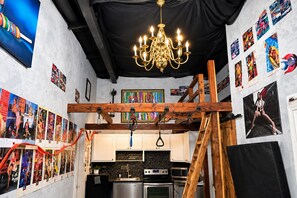 Een keuken met een zwart betegelde spatwand, roestvrijstalen apparatuur en een houten plafondconstructie.