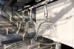 A row of empty wine glasses hanging from a metal rod. - Downtown Chop Shop house, HUGE garage pets allowed (fort smith)