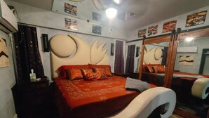 A bedroom with a large bed, a mirror, and a ceiling fan.