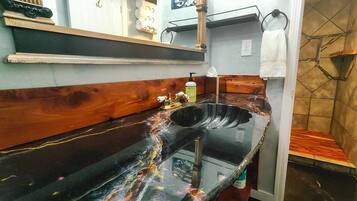Une salle de bain avec un lavabo en marbre noir, un meuble-lavabo en bois et un porte-serviettes.