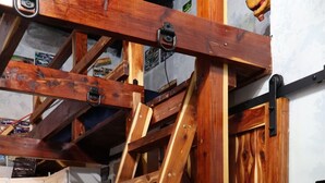 A wooden ladder leaning against a wall with a kitchen area in the background.