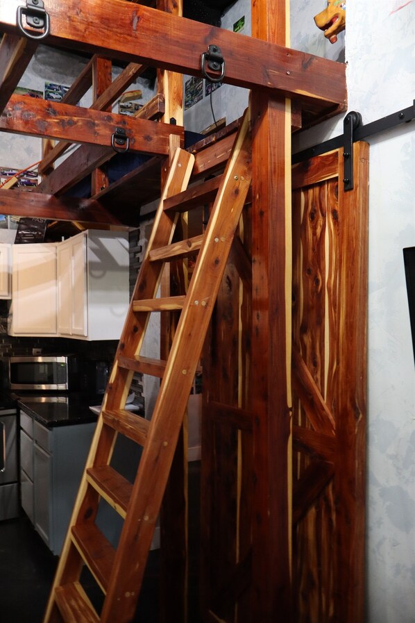 A wooden ladder leaning against a wall with a kitchen area in the background. - Downtown Chop Shop house, HUGE garage pets allowed (fort smith)