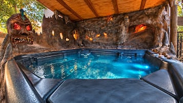 Een hottub met een ruige stenen achtergrond, een houten dak en een metalen poort.
