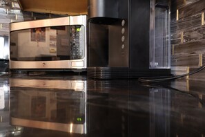 A kitchen with a stainless steel microwave, a black range hood, and a wooden wall. - Downtown Chop Shop house, HUGE garage pets allowed (fort smith)