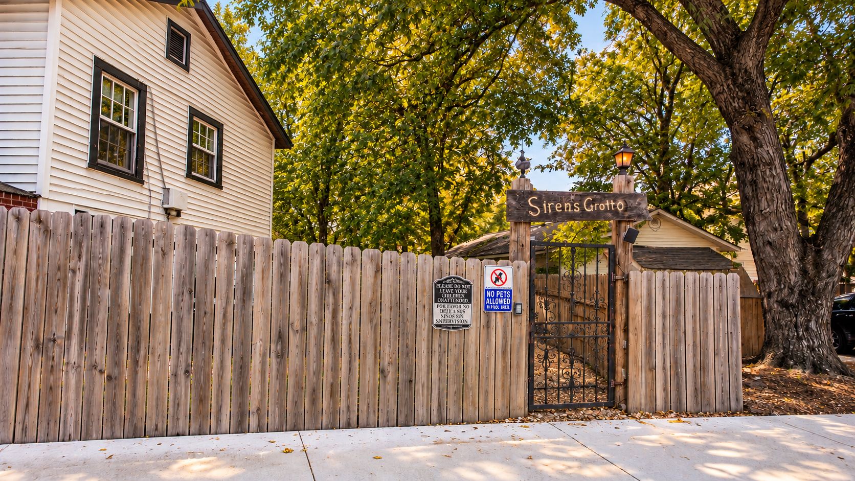 A gated entrance with a wooden fence, a sign reading 'Sirens Groto,' and a 'No Pets Allowed' sign.
