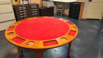 A round table with a red top and wooden edges, surrounded by drawers and a printer in a workshop-like setting.