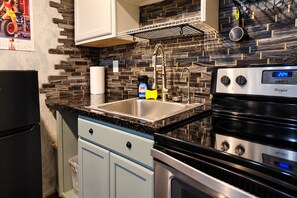 A kitchen with a stainless steel sink, a Whirlpool dishwasher, and a black stove. - Downtown Chop Shop house, HUGE garage pets allowed (fort smith)