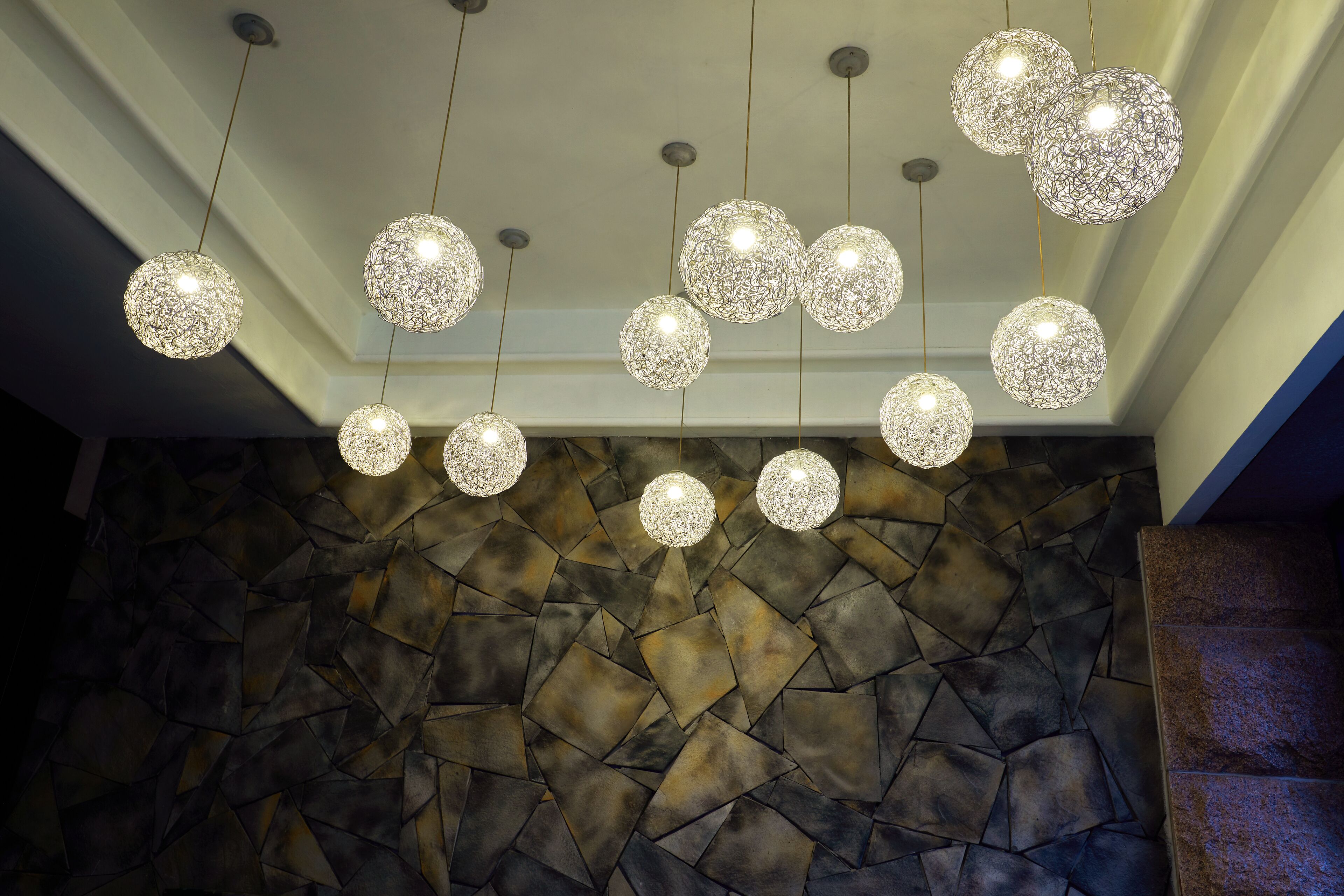 Un plafond orné de plusieurs lustres sphériques et un mur en pierre.