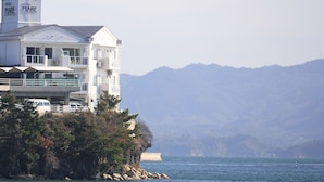 A hotel with a white exterior, located on a cliff overlooking a body of water. - hotelmare (Kure)