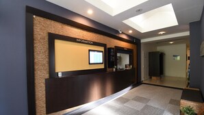 A reception area with a digital information board, a reception desk, and a view into the front area. - hotelmare (Kure)