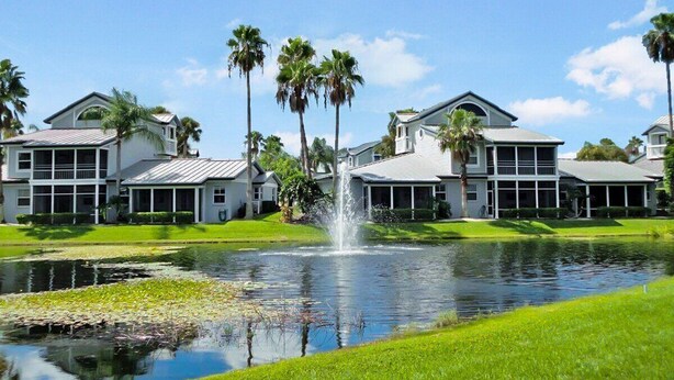 A waterfront property with multiple houses, a central fountain, and a pond with lily pads. - Relaxing Siesta Key condo - pickleball - 2 heated pools - beach access - GBB 1344 (Siesta Key)