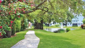 A pathway leading to a building with a pond and lush greenery. - Spacious condo on Siesta Key with beach access - GBB 1200 (Siesta Key)