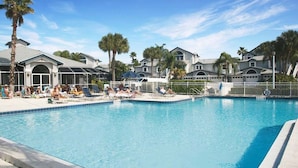 A swimming pool with lounge chairs and palm trees, surrounded by buildings with large windows and a clear sky. - Spacious condo on Siesta Key with beach access - GBB 1200 (Siesta Key)