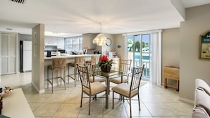 A modern kitchen with a dining area, featuring a glass table, chairs, and a hanging light fixture. - Spacious condo on Siesta Key with beach access - GBB 1200 (Siesta Key)