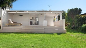 Ein Haus mit einer überdachten Terrasse, einem Liegestuhl und einem großen Blumenkasten.
