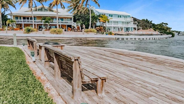 A waterfront property with a wooden boardwalk, a pool, and a building with a white facade and balconies. - Spacious 2BR Siesta Key condo with beach access - GBB 1241 (Siesta Key)