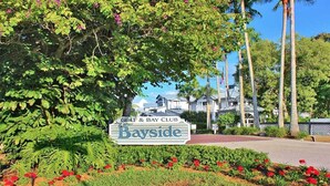 A sign for Gulf & Bay Club Bayside with a view of the resort buildings and palm trees. - Spacious 2BR Siesta Key condo with beach access - GBB 1241 (Siesta Key)