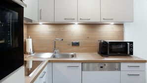 Una cucina moderna con mobili bianchi, un lavello in acciaio inossidabile, un forno a microonde integrato e una lavastoviglie.