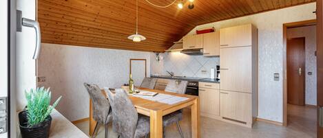 Una cocina moderna con armarios de madera, una mesa de comedor con sillas y un techo con vigas a la vista.