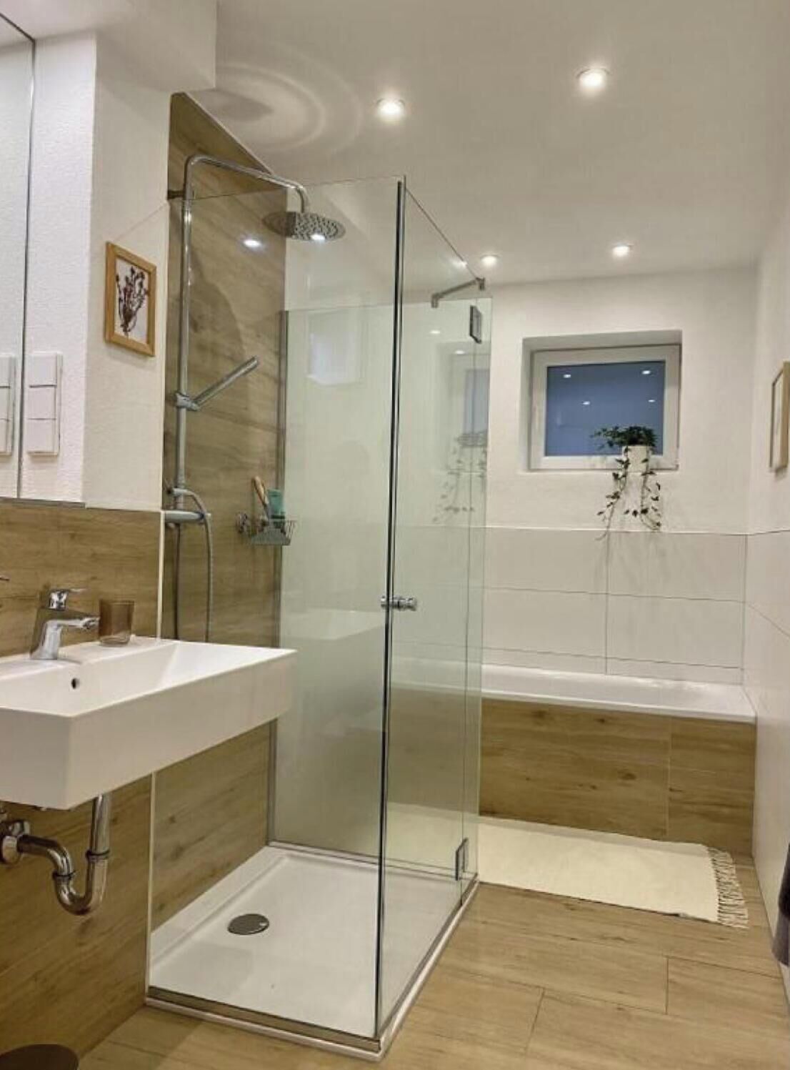 Ein modernes Badezimmer mit einer Duschkabine, einem freistehenden Waschbecken und einer Badewanne.