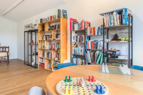 A room with a wooden table, a chessboard, and two bookshelves filled with books.