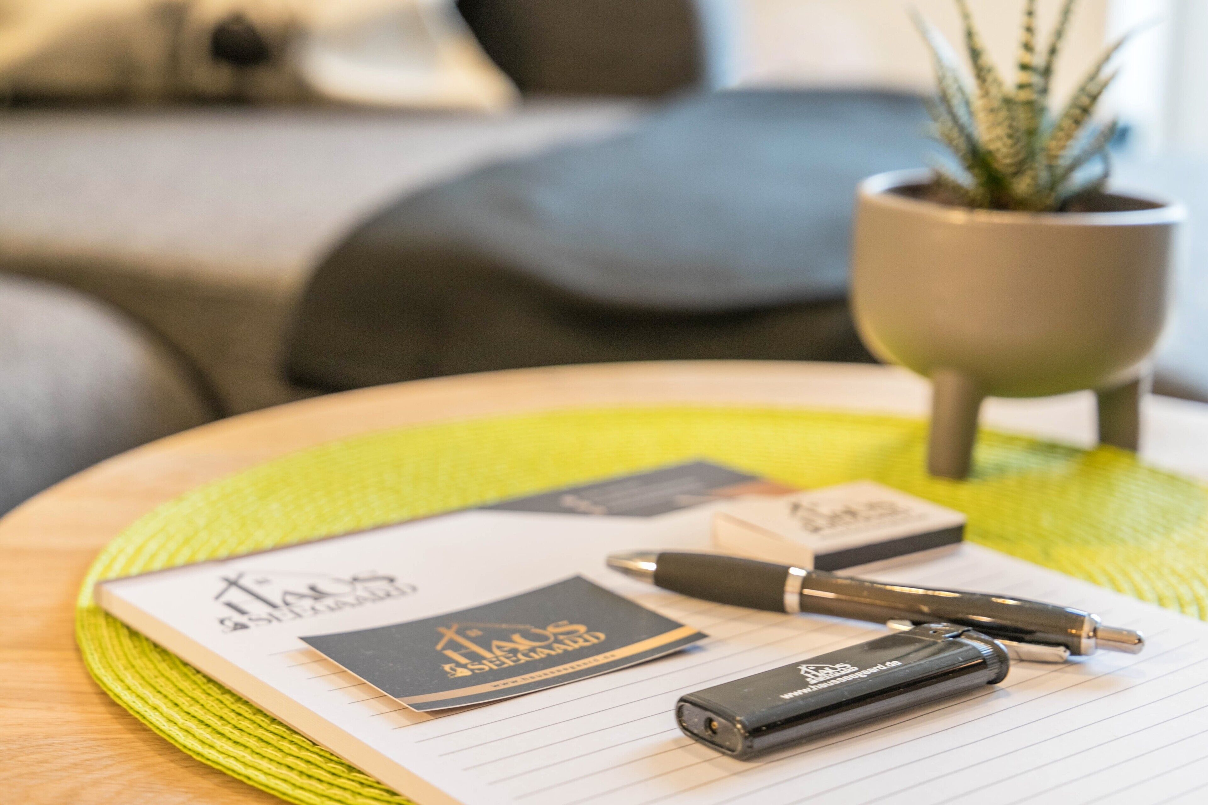 Een notitieboek, visitekaartjes, een pen en een powerbank op een tafel met een geweven placemat.